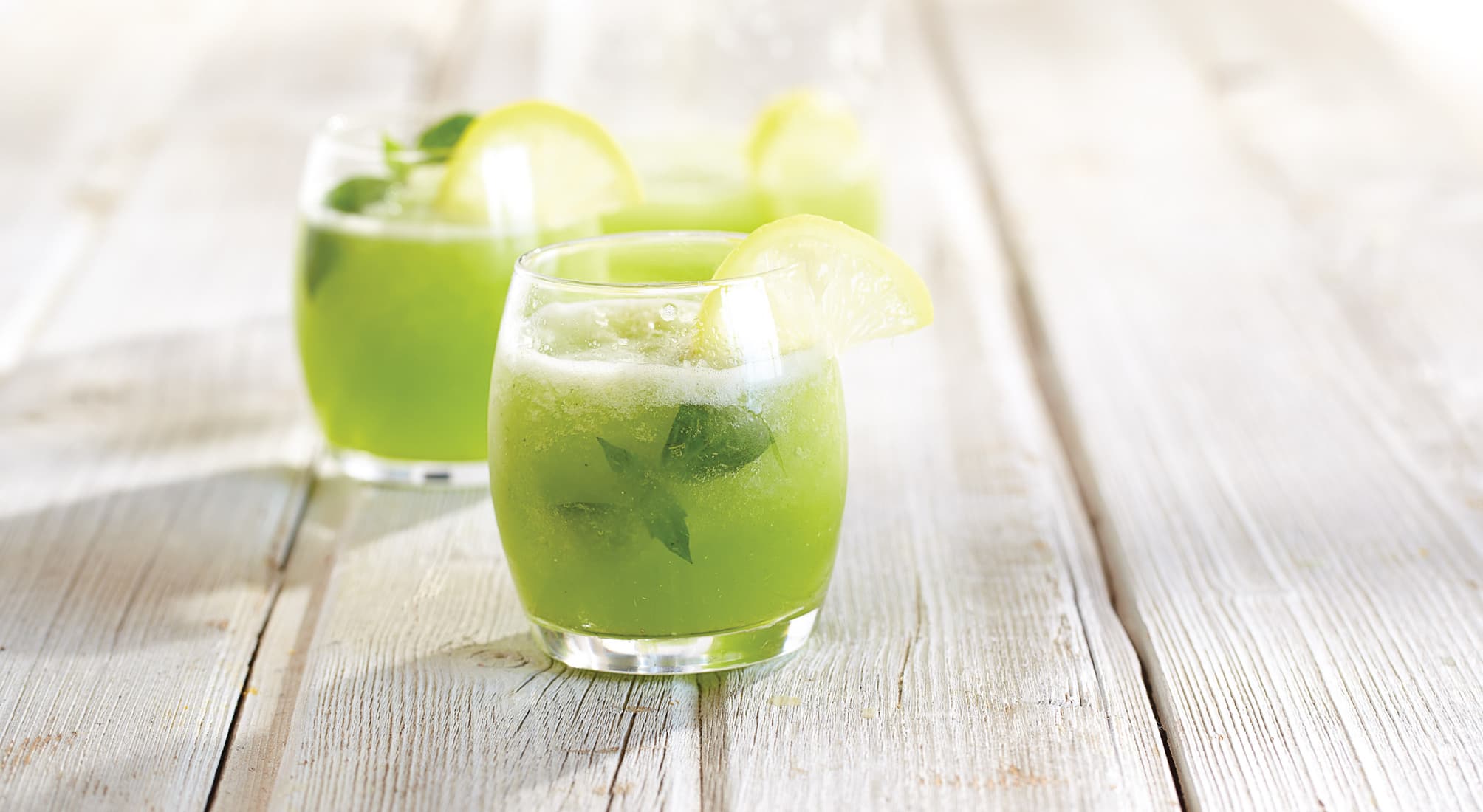 Glasses of frosty basil lemonade on picnic table
