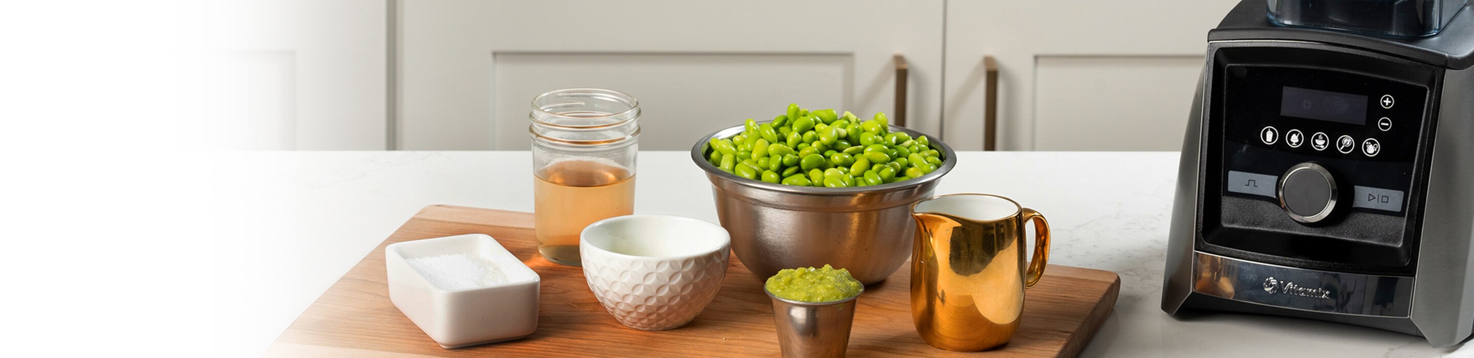 A counter setting with a Vitamix blender and cutting board with refreshments