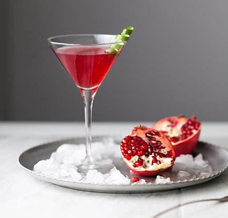 Pomegranate Cosmopolitan Cocktail in a glass martini glass with a lime twist