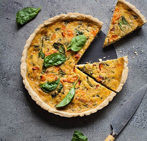Quiche au saumon fumé et aux épinards smoked salmon & spinach quiche with a slice taken out of it