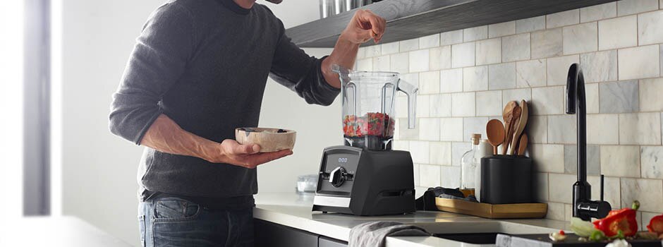 Man sprinkling ingredients into a Vitamix